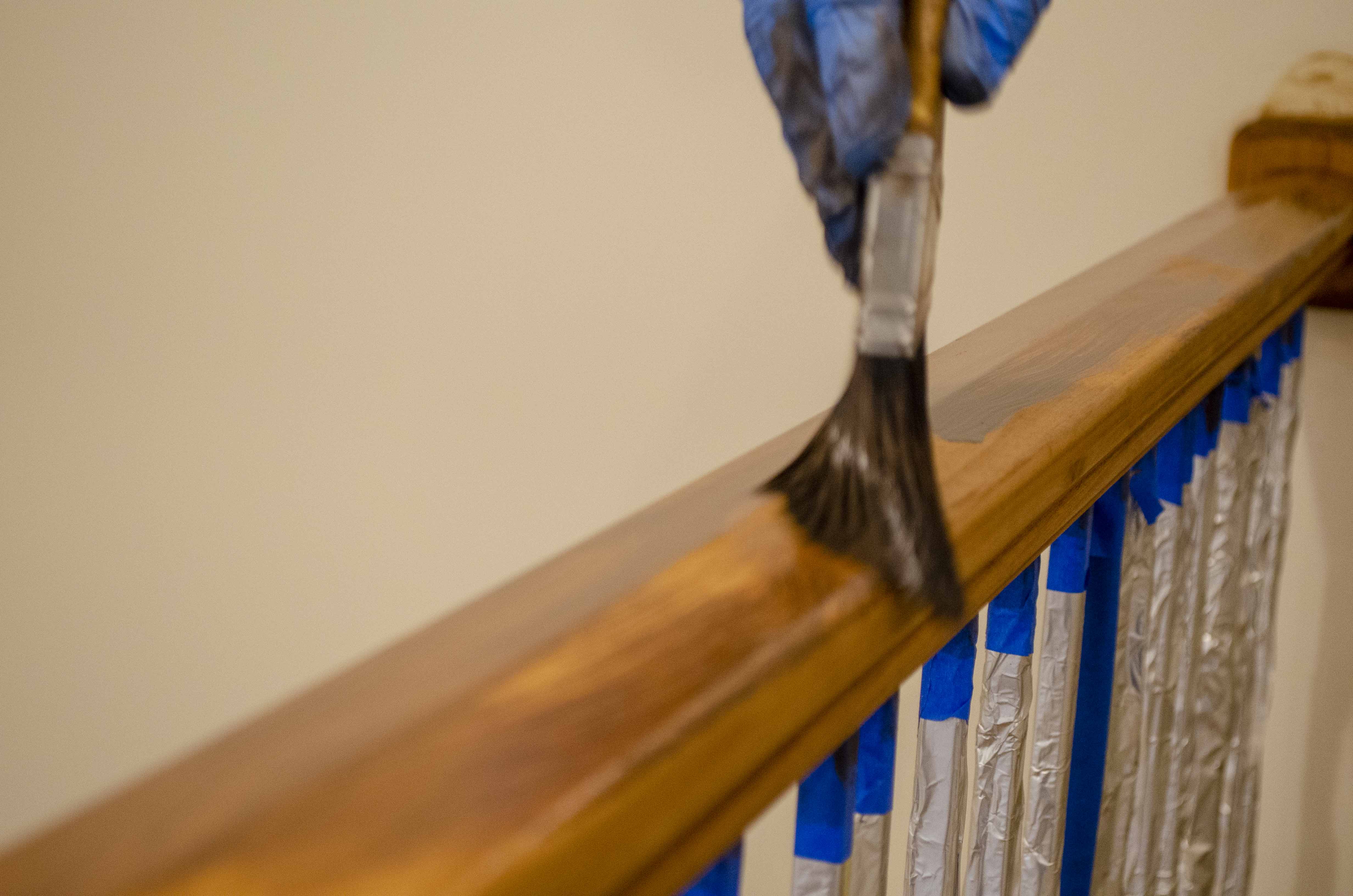 wood railing being stained with paint brush